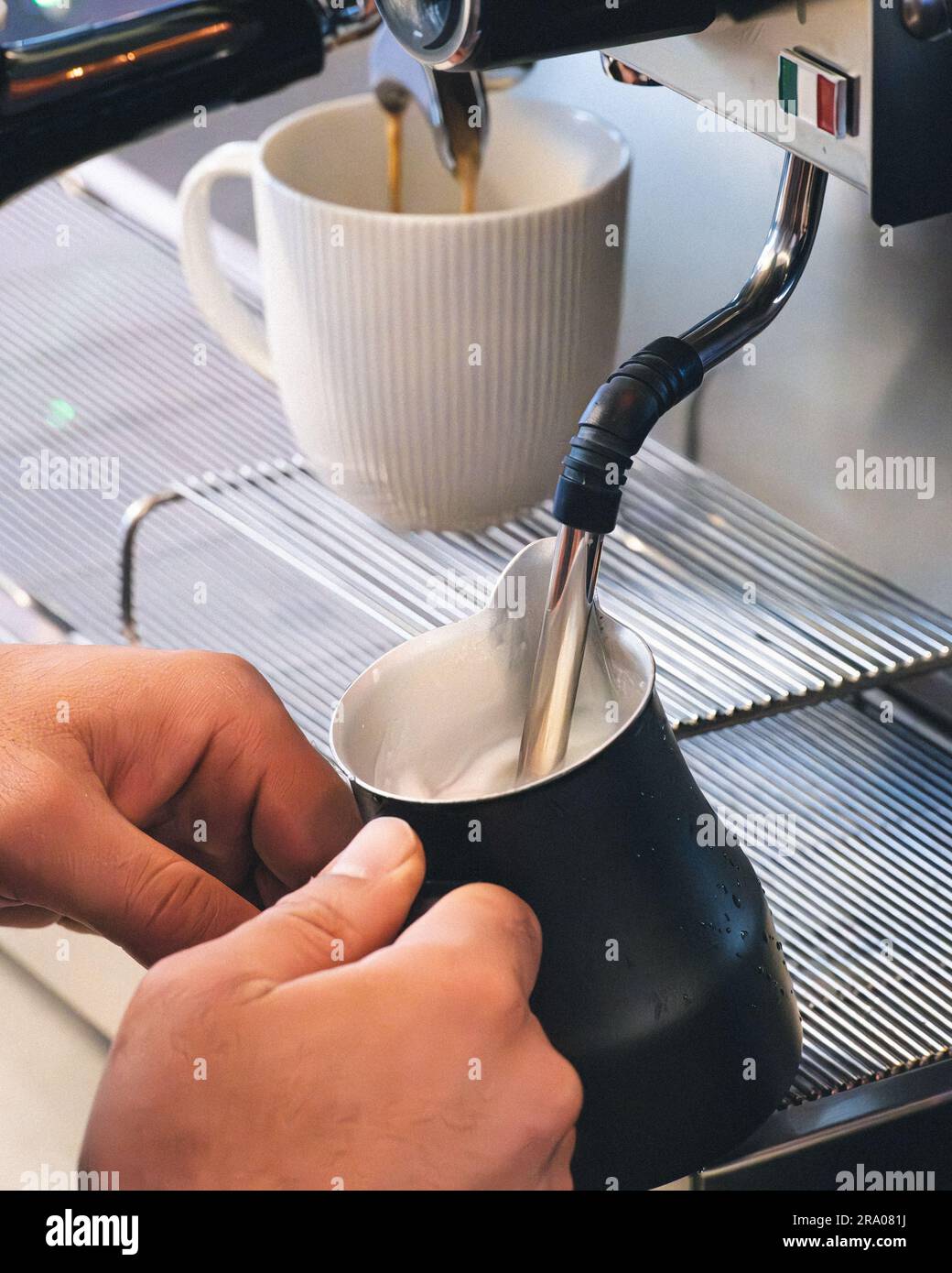 https://c8.alamy.com/comp/2RA081J/a-professional-barista-pouring-steamed-milk-from-a-coffee-machine-into-a-jug-2RA081J.jpg