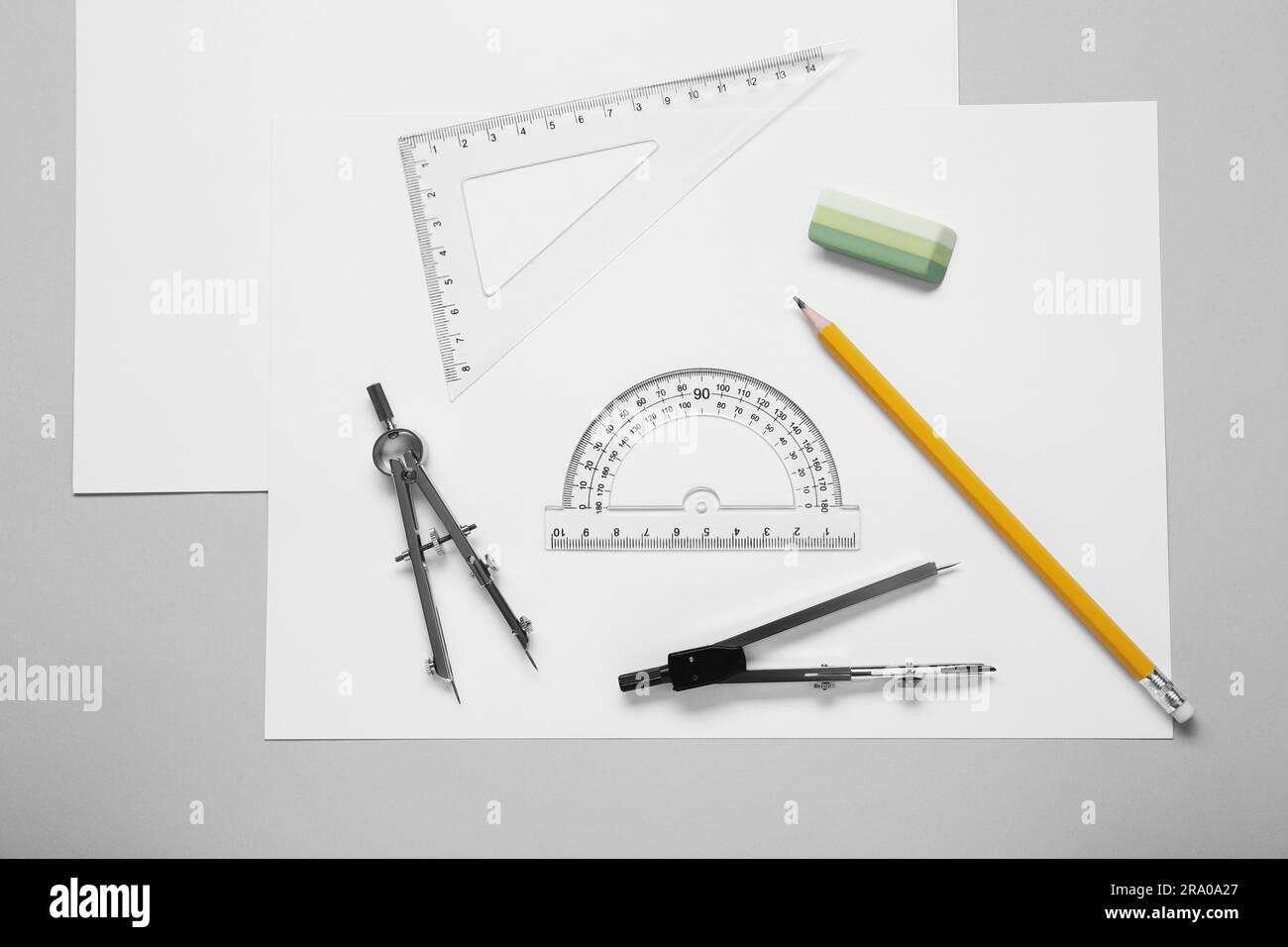 Different rulers, pencil and compasses on light grey background, flat lay Stock Photo