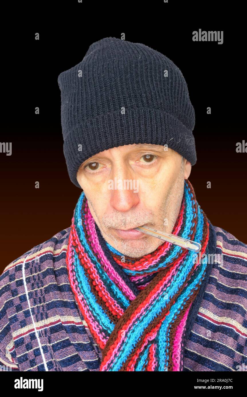 Sick man with the flu and temperature, wearing a cap and a woolen scarf, on dark background