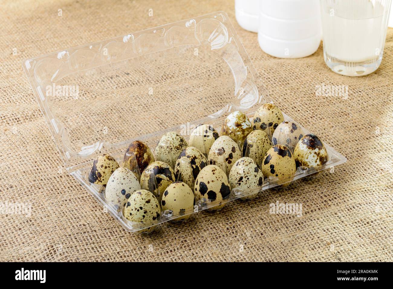 Quail eggs in a transparent plastic container, on a burlap tablecloth Stock Photo