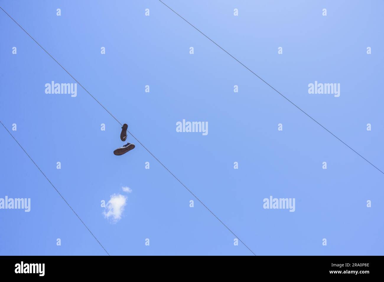 Shoes attached to an electric wire with a blue sky background Stock