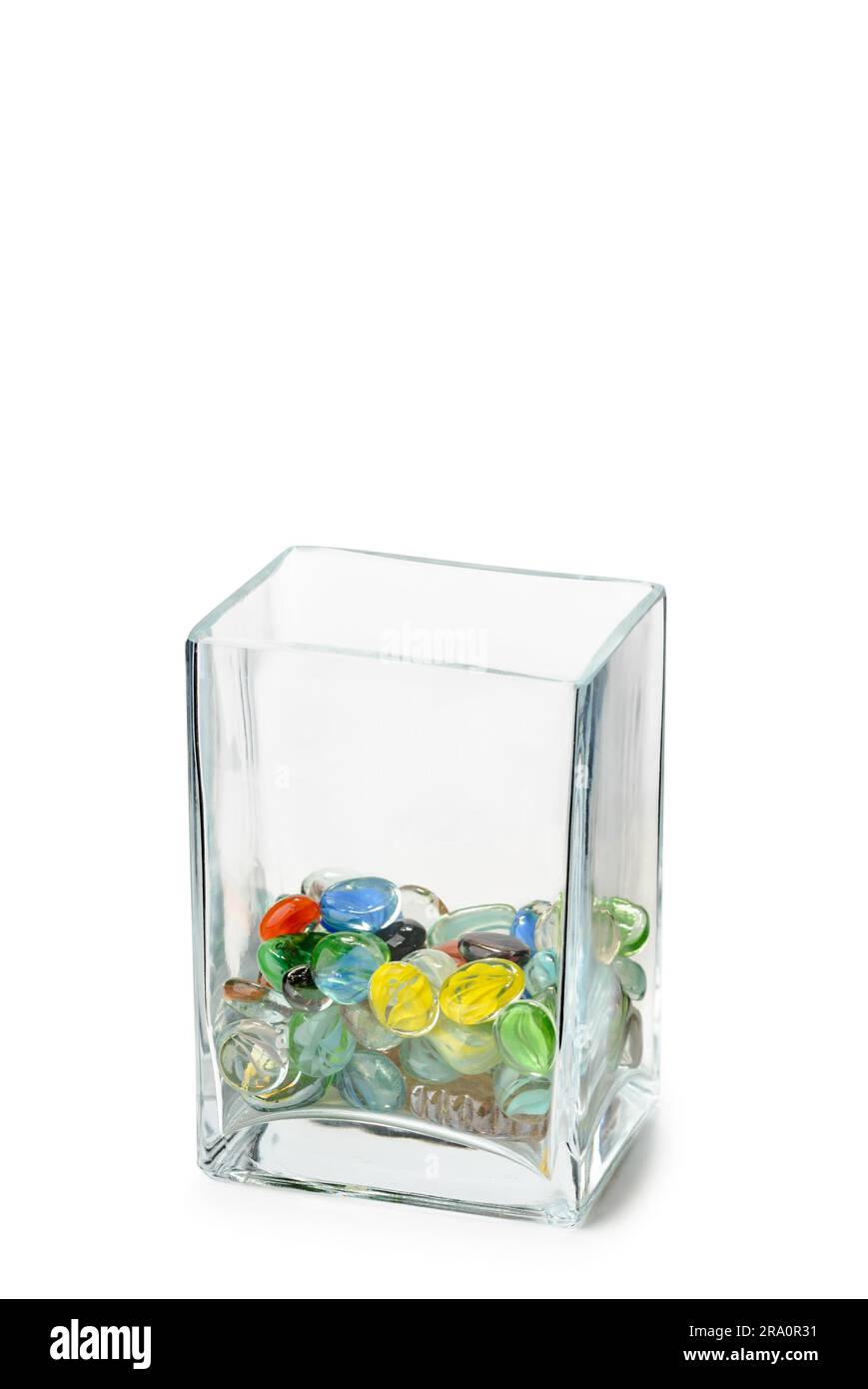 A Parallelepipedic transparent crystal vase isolated on white background, half full of colored glass beads Stock Photo