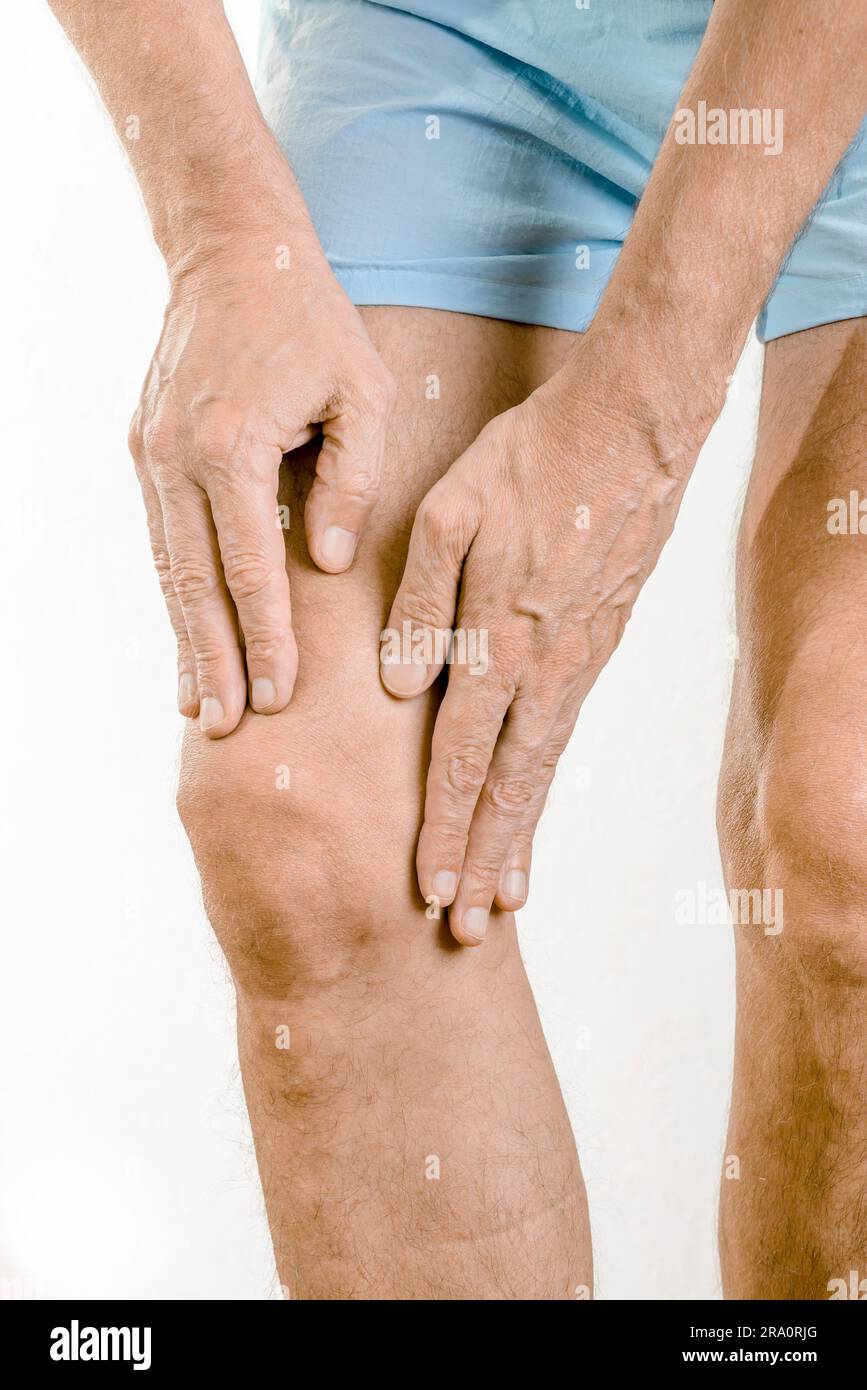 Athlete man massaging a painful quadriceps and the knee after a sport accident. It could be a quadriceps tendinopathy, a muscle elongation, a medial Stock Photo