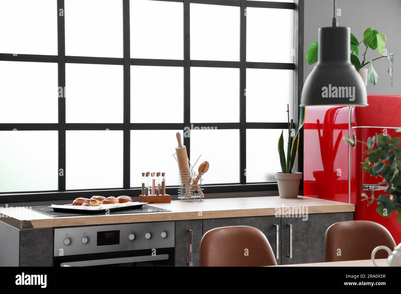 Interior of modern kitchen with electric stove, grey counters and red ...