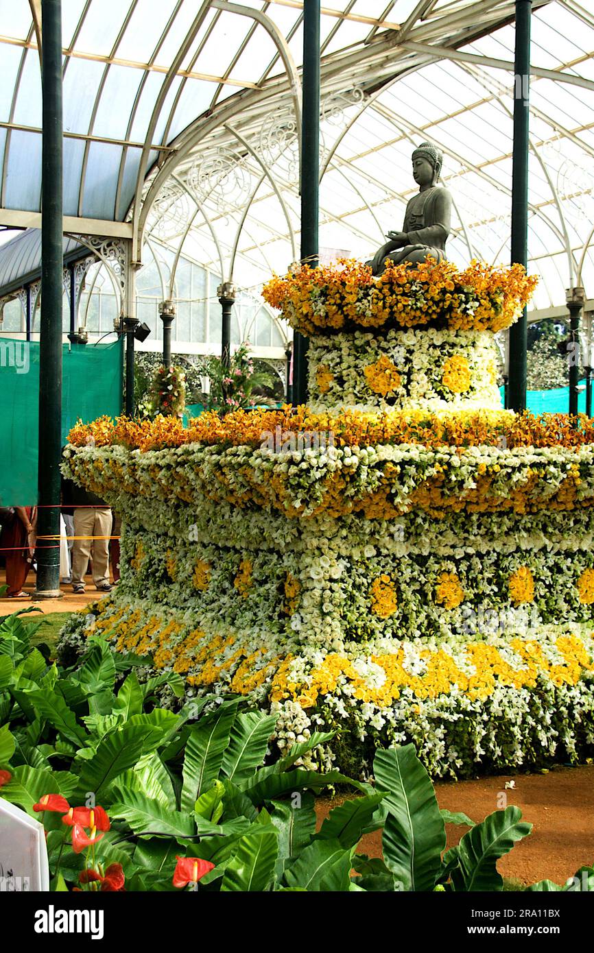 Statue of Buddha sitting on pedestal decorated with flowers at