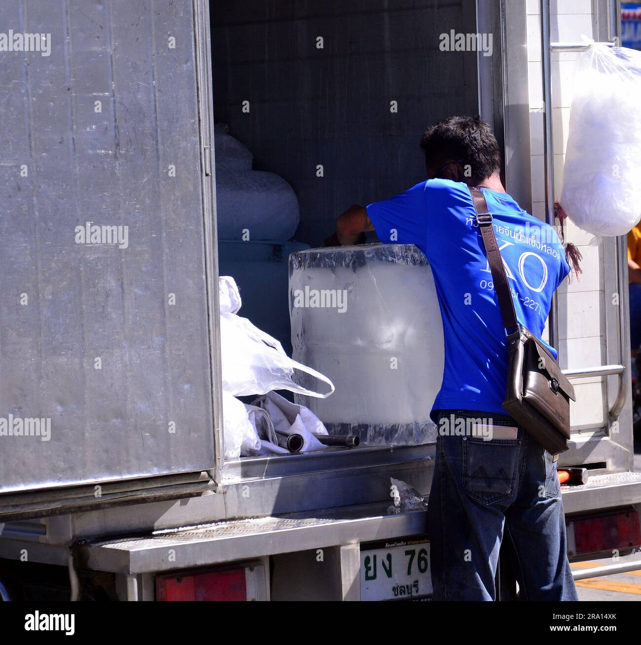 A delivery worker holds a very large block of ice he is delivering from