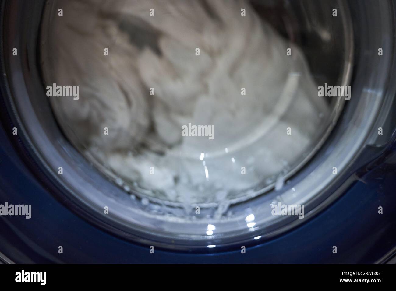 Round washing machine drum with white linen. Laundry is machine washable. High quality photo