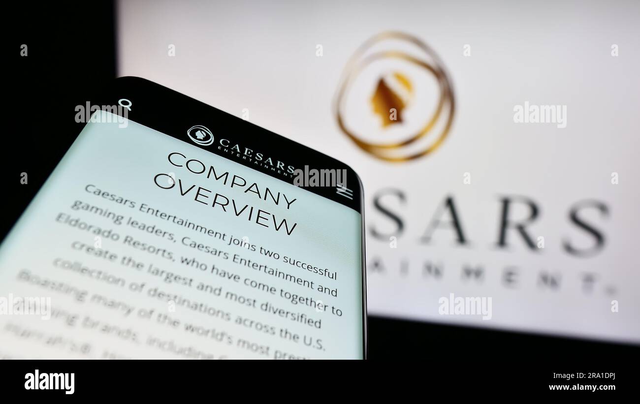 Smartphone with website of US company Caesars Entertainment Inc. on screen in front of business logo. Focus on top-left of phone display. Stock Photo