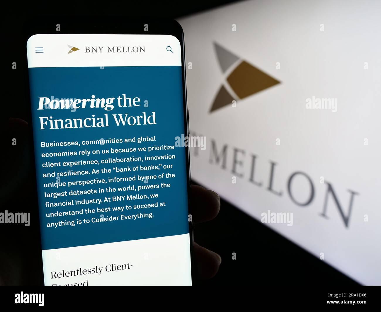 Person holding cellphone with webpage of The Bank of New York Mellon Corporation (BNY) on screen with logo. Focus on center of phone display. Stock Photo