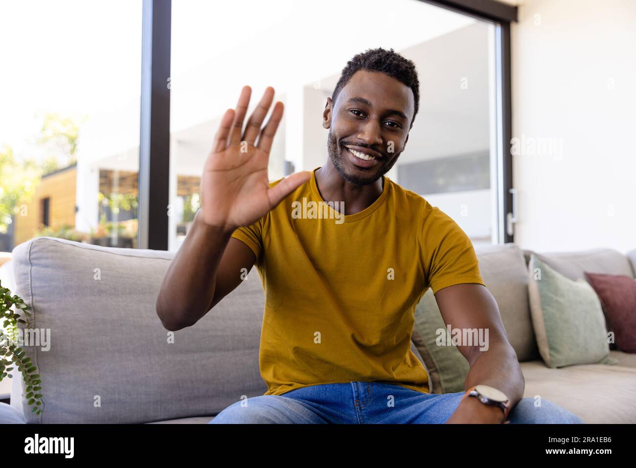Happy african american man making video call and waving in living room ...