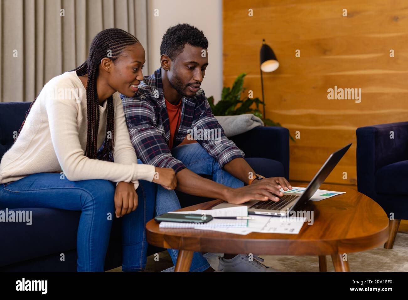 Happy african american couple doing paperwork using laptop at home ...