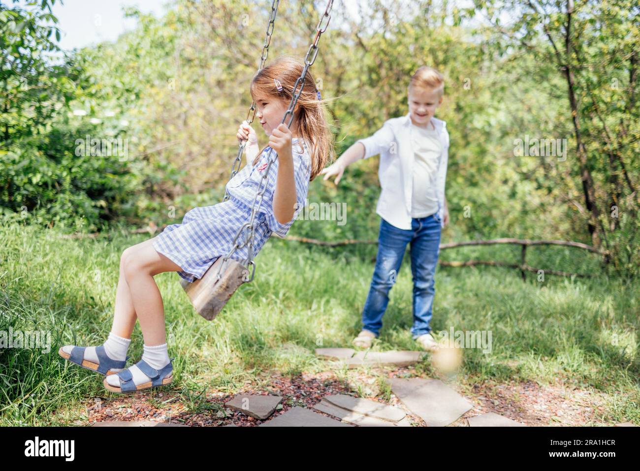 Pretty schoolboy in jeans and white shirt is rocking his younger sister