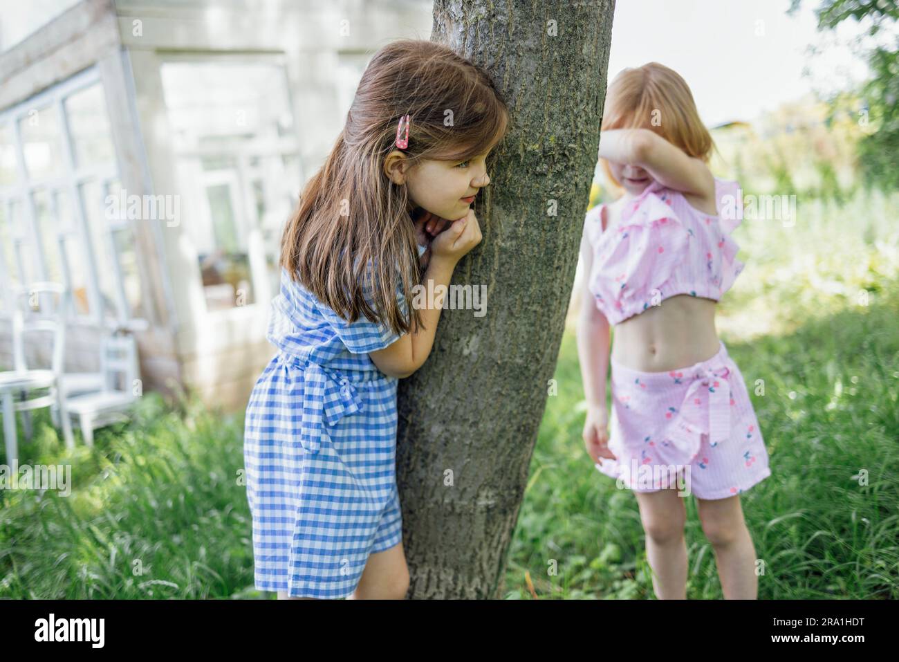 Small kids play hideandseek outdoors in the garden. A cute girl is