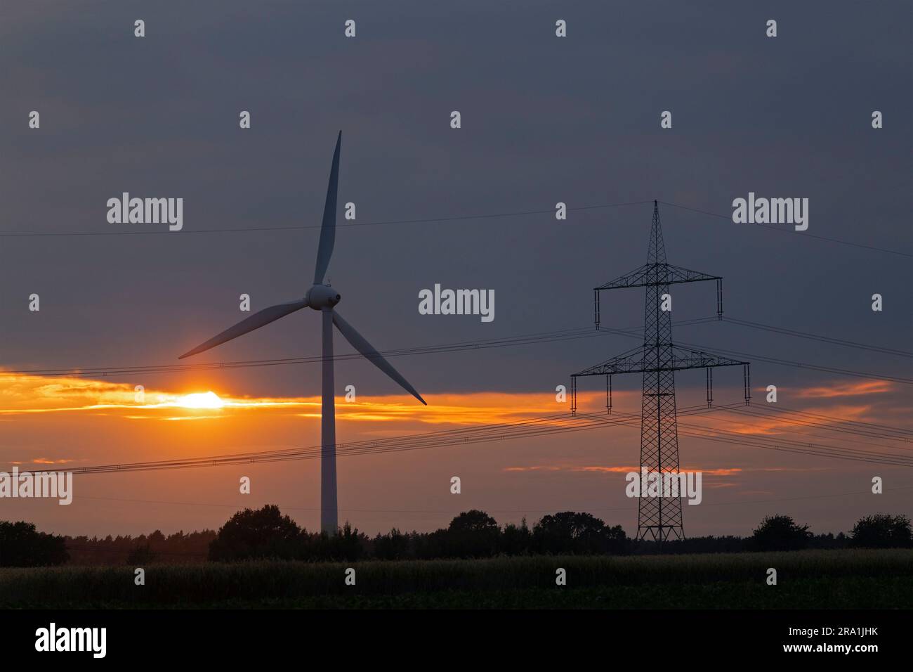 Wind power station and pylon in front of evening sky, afterglow, sunset, clouds, Melbeck, Ilmenau joint community, Lower Saxony, Germany Stock Photo