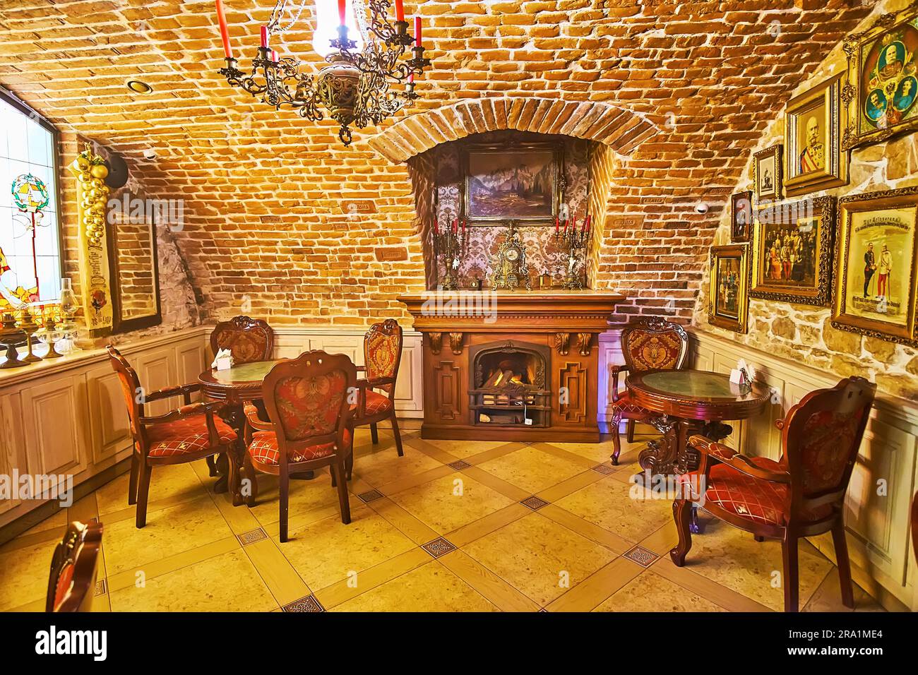 CHERNIVTSI, UKRAINE - JULY 16, 2021: The retro cellar restaurant with brick walls, carved wooden fireplace and furniture, on July 16 in Chernivtsi Stock Photo