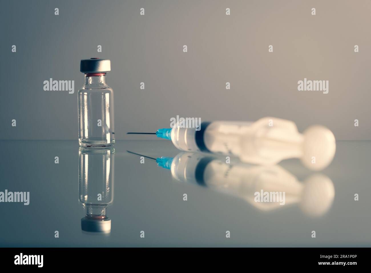 An ampoule and a syringe are placed on a shiny background, soft lights to create an environment to discover, research for rare diseases. Stock Photo