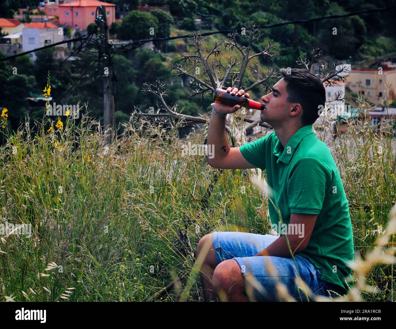 Man dressed in green drinking a beer in the woods. Stock Photo