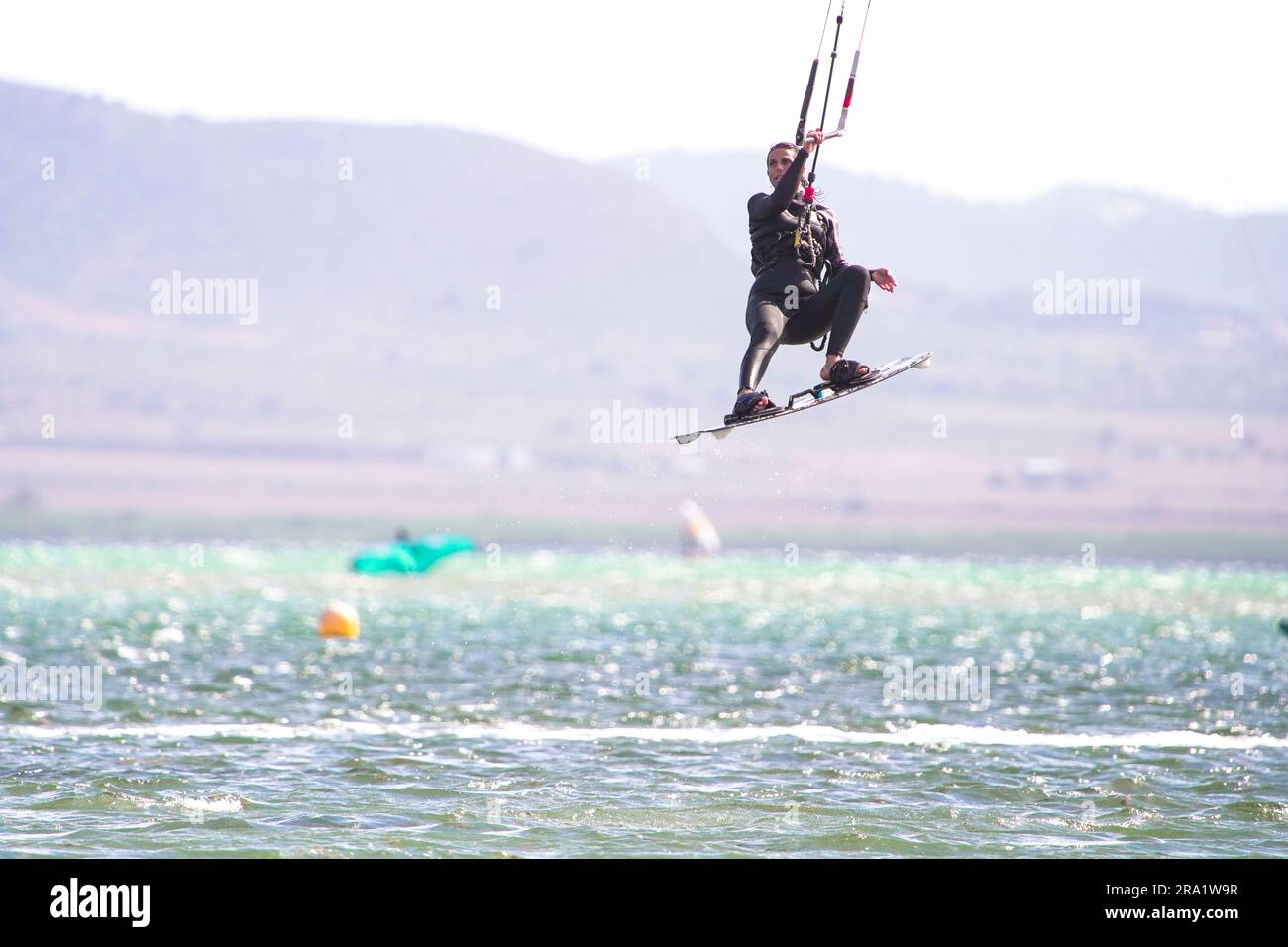 Woman do tricks with her board practicising kitesurf jump in the air