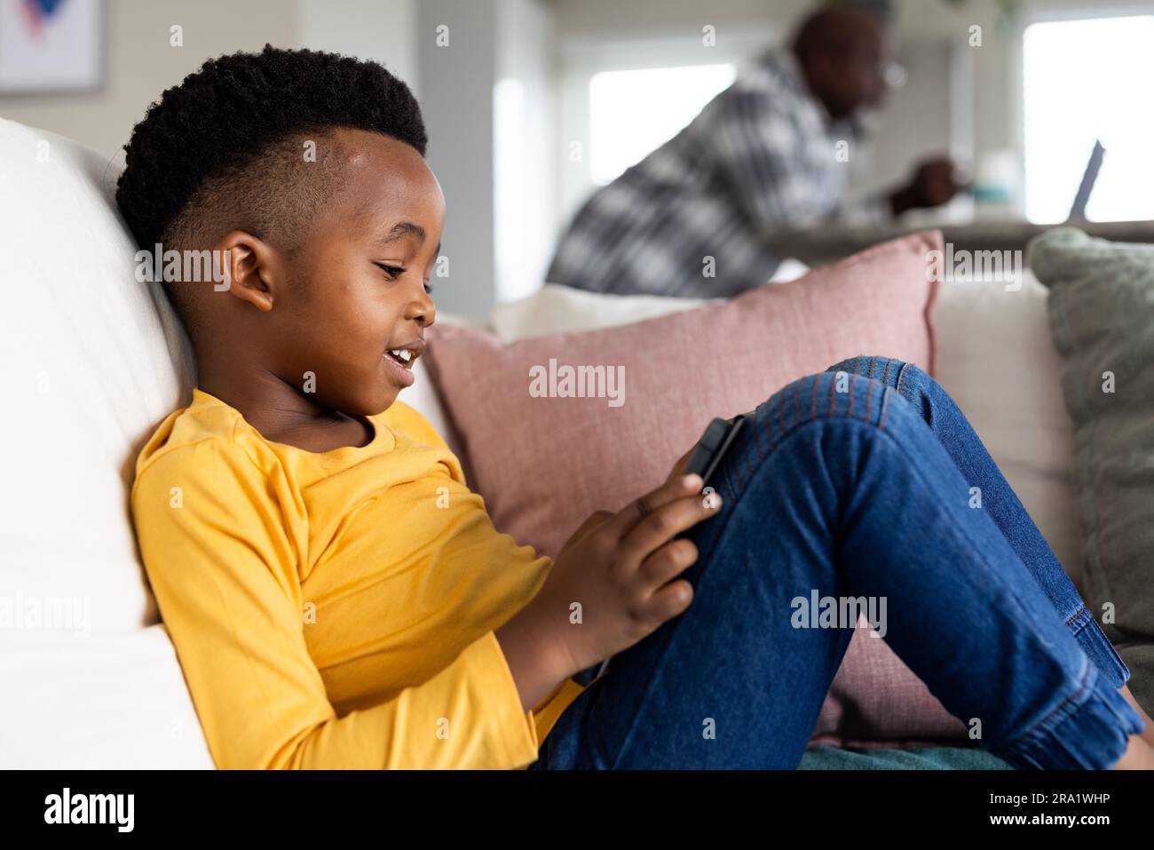 Happy african american boy sitting on sofa and using tablet Stock Photo ...