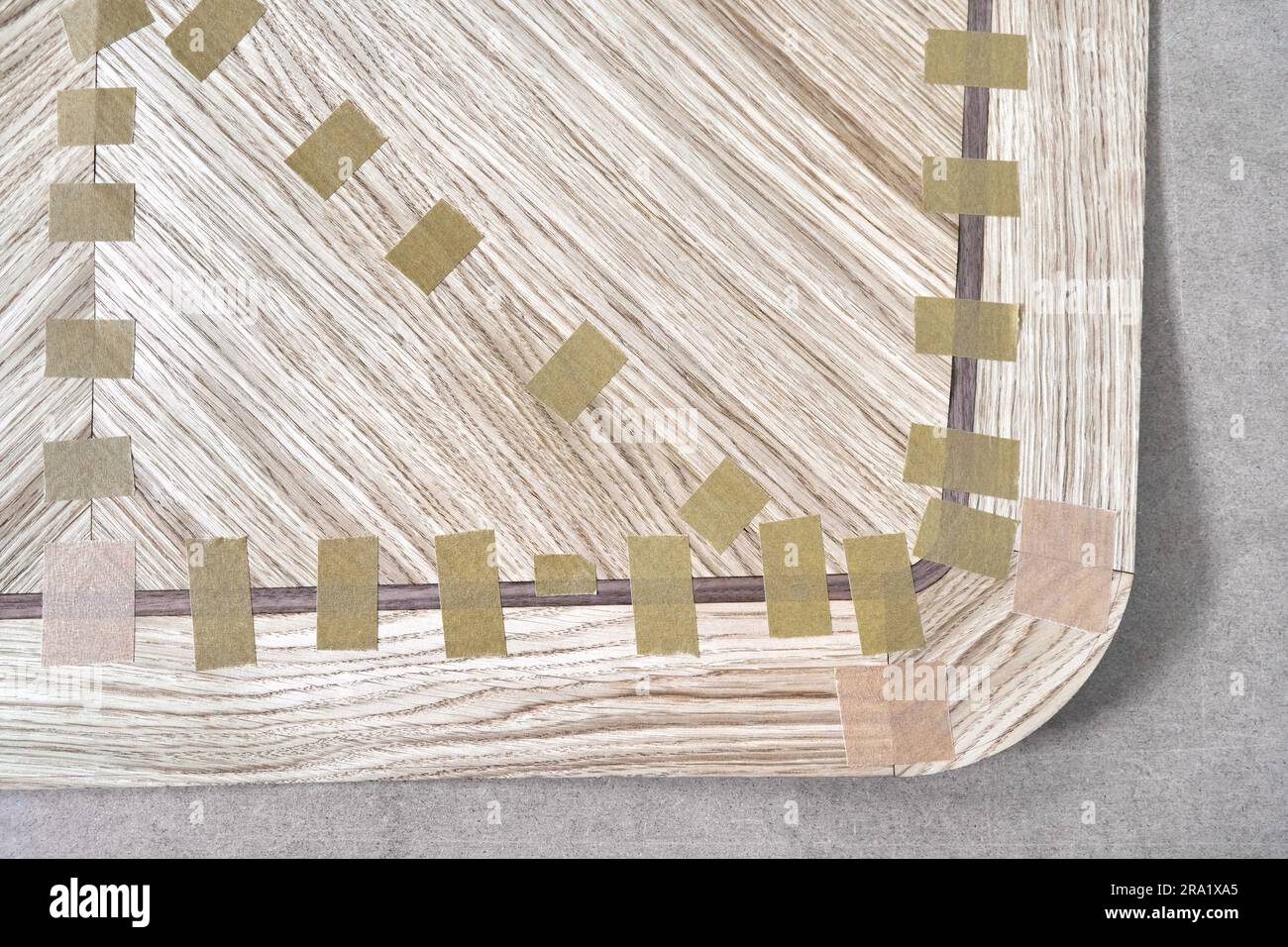 Jointed veneer with tape into canvas for table top of dining table with geometric pattern on workbench in workshop upper close view Stock Photo