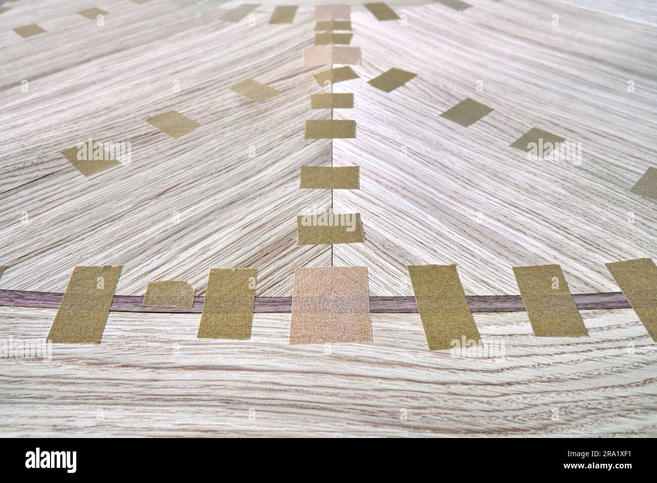 Jointed veneer with tape for table top of dining table with geometric pattern on workbench in workshop closeup Stock Photo