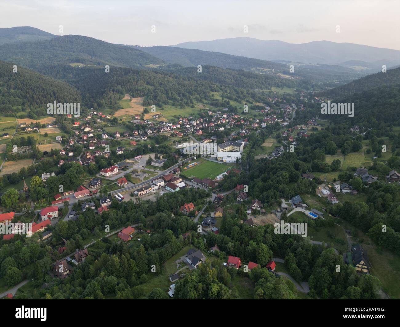 An aerial view with a quaint town nestled in a lush forested area ...