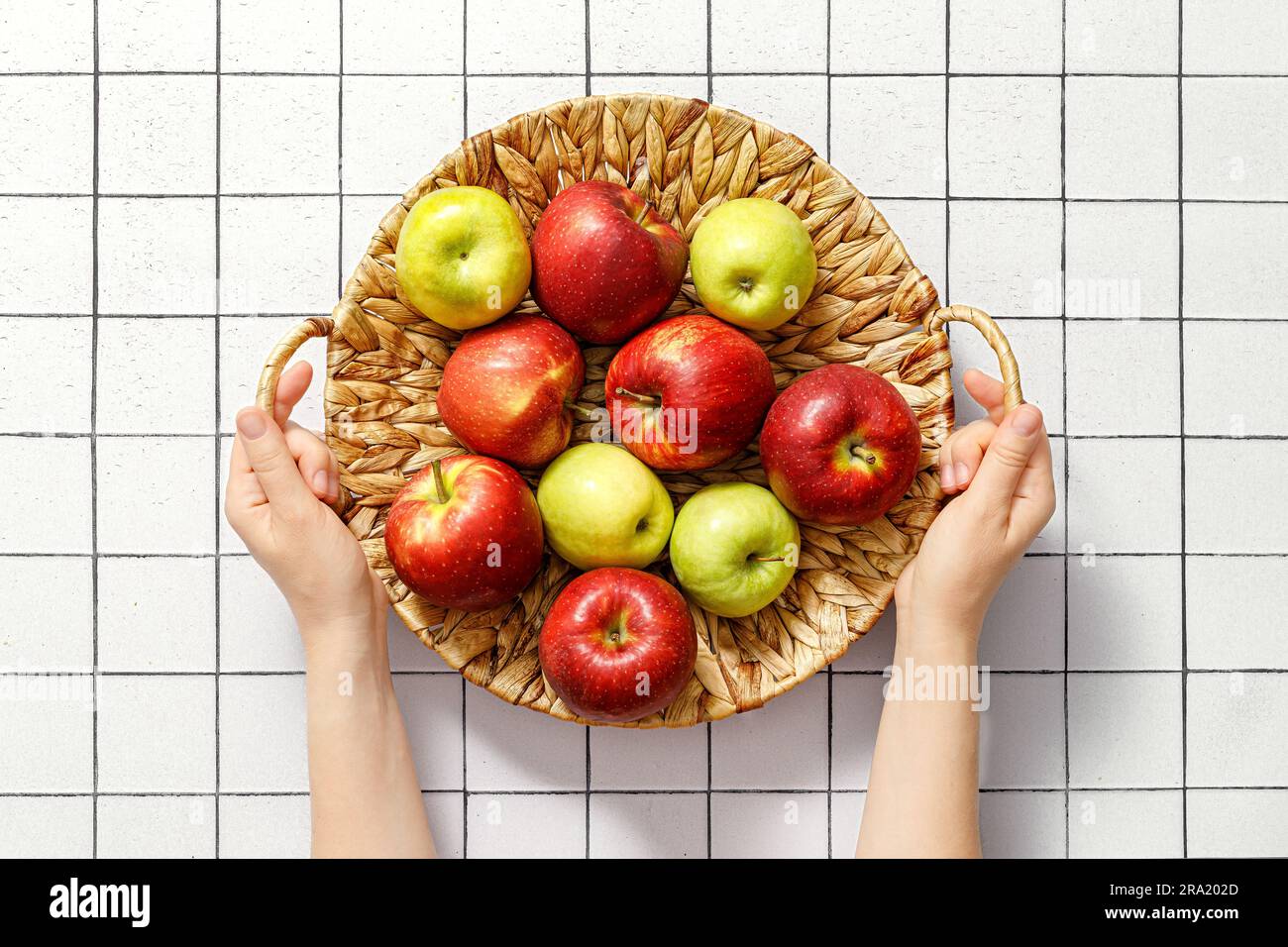Apples. Harvest of fresh juicy red and green apple fruits in a basket in woman hands, copy space, top view Stock Photo