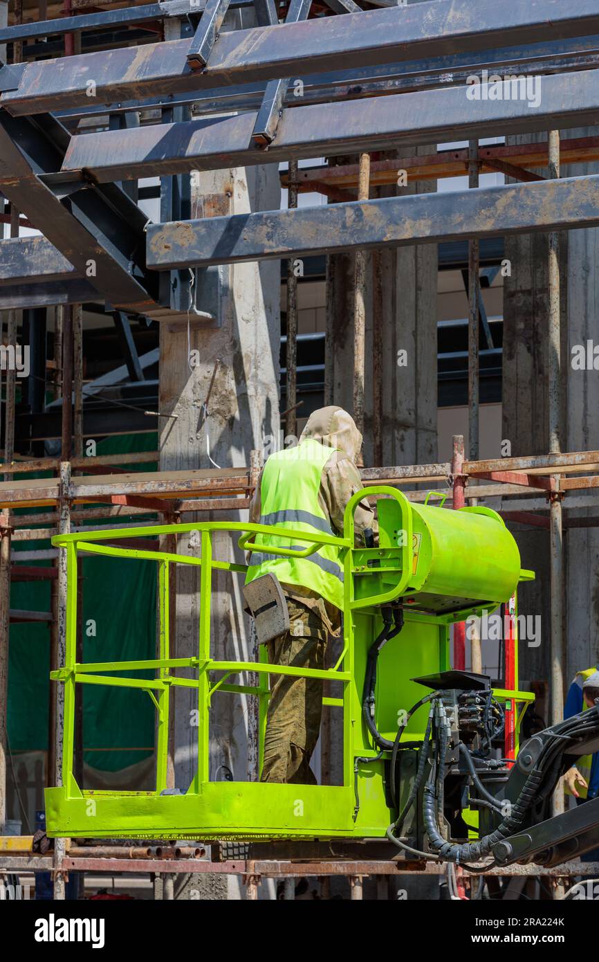 Man - a builder works at the site of the crane at height. Construction ...