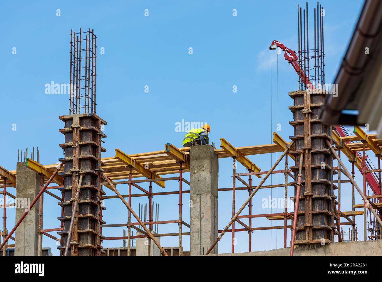 A male construction worker stands on reinforced concrete beams at a ...