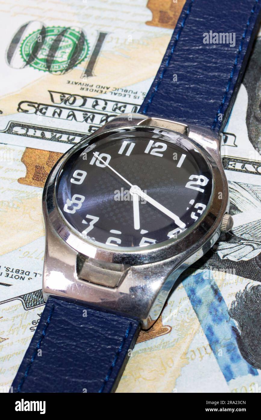 Blue wrist watch on dollars close up, the price of time Stock Photo