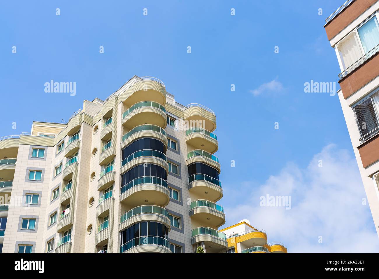 Exterior of a modern apartment building against a blue sky with clouds ...