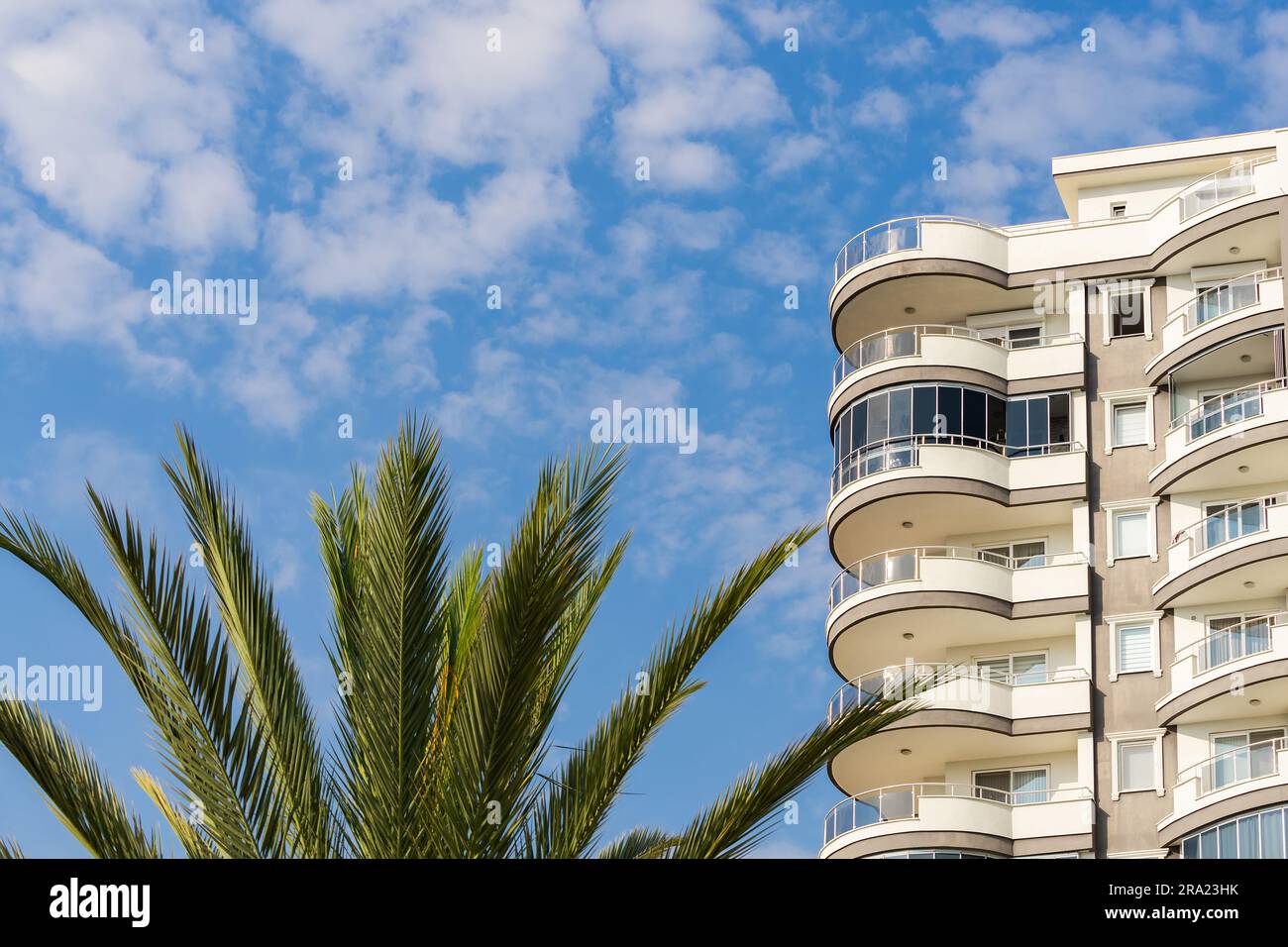 Exterior of a modern apartment building against a blue sky with clouds ...