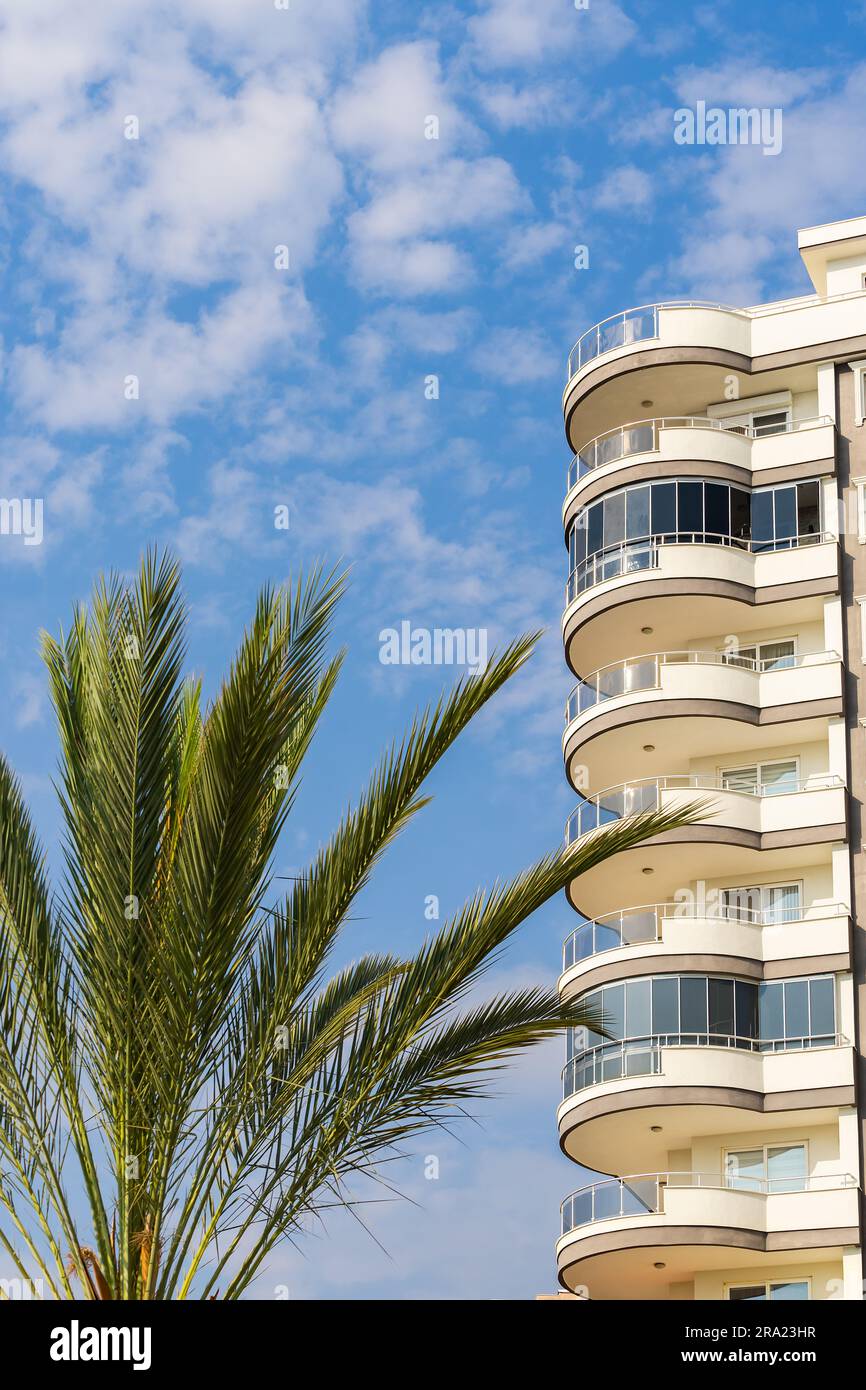 Exterior of a modern apartment building against a blue sky with clouds ...