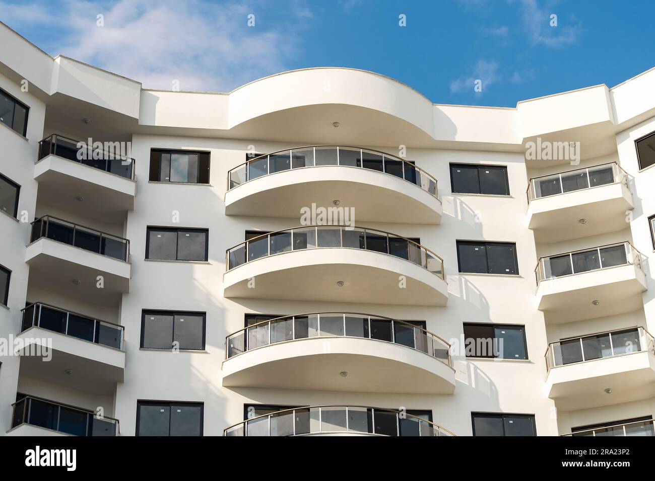 Exterior of a modern apartment building against a blue sky with clouds ...