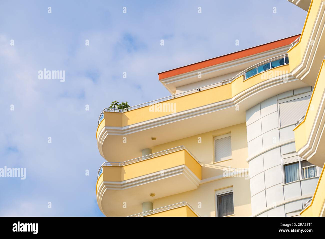 Exterior of a modern apartment building against a blue sky with clouds ...