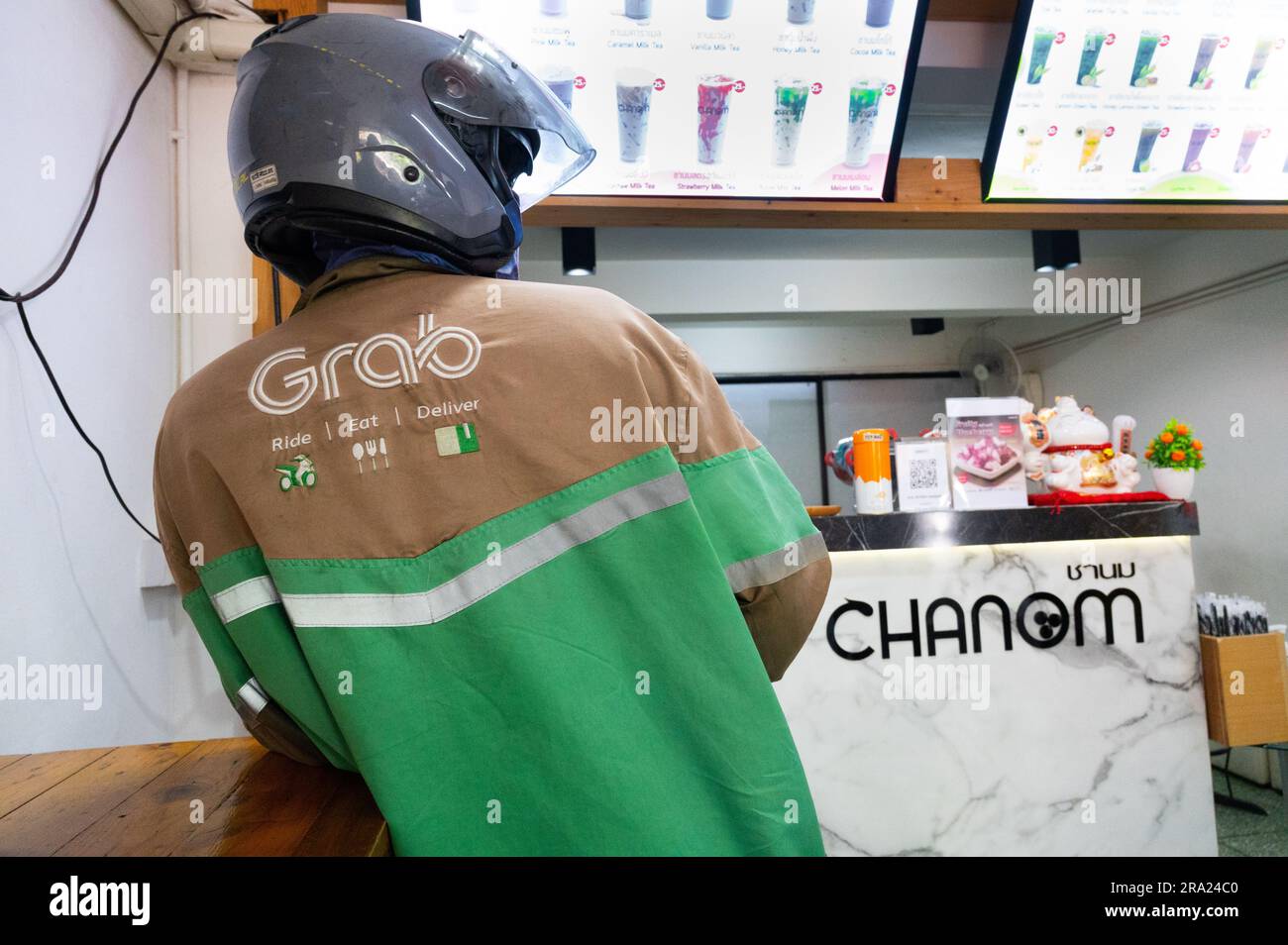 Grab food delivery moped driver waits for order in bubble tea cafe