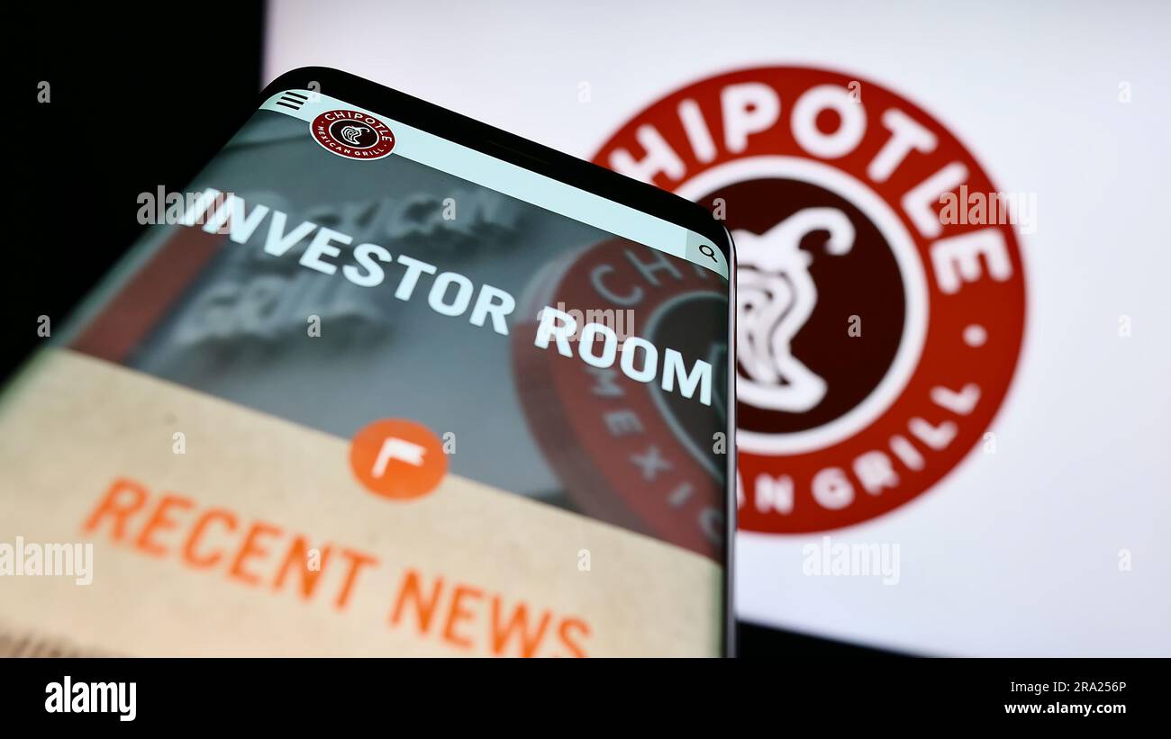 Smartphone with website of US company Chipotle Mexican Grill Inc. on screen in front of business logo. Focus on top-left of phone display. Stock Photo