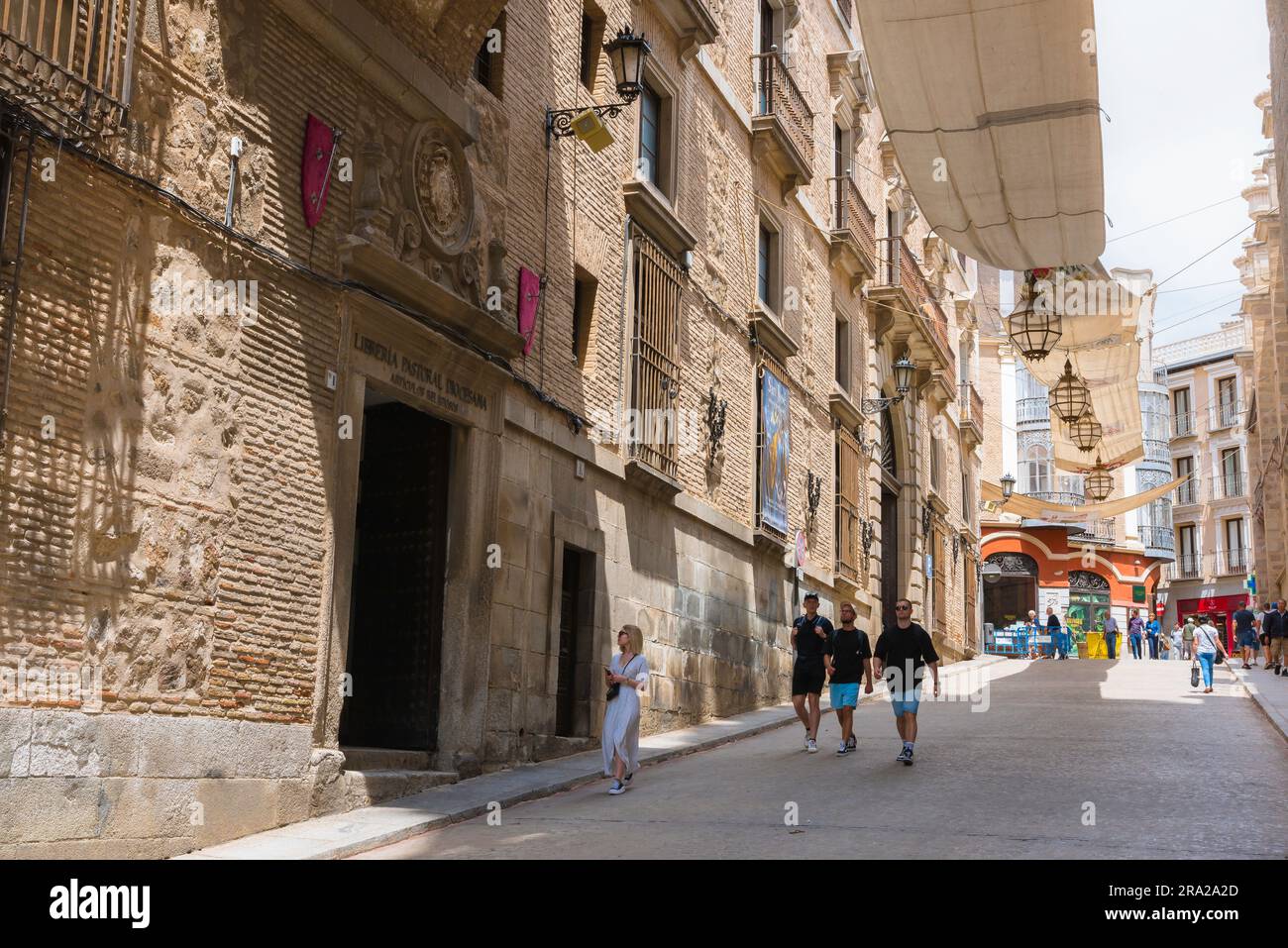 Toledo, view in summer of people walking past the Archbishop's Palace in the Calle Arco de Palacio in the historic Old Town area of Toledo, Spain Stock Photo