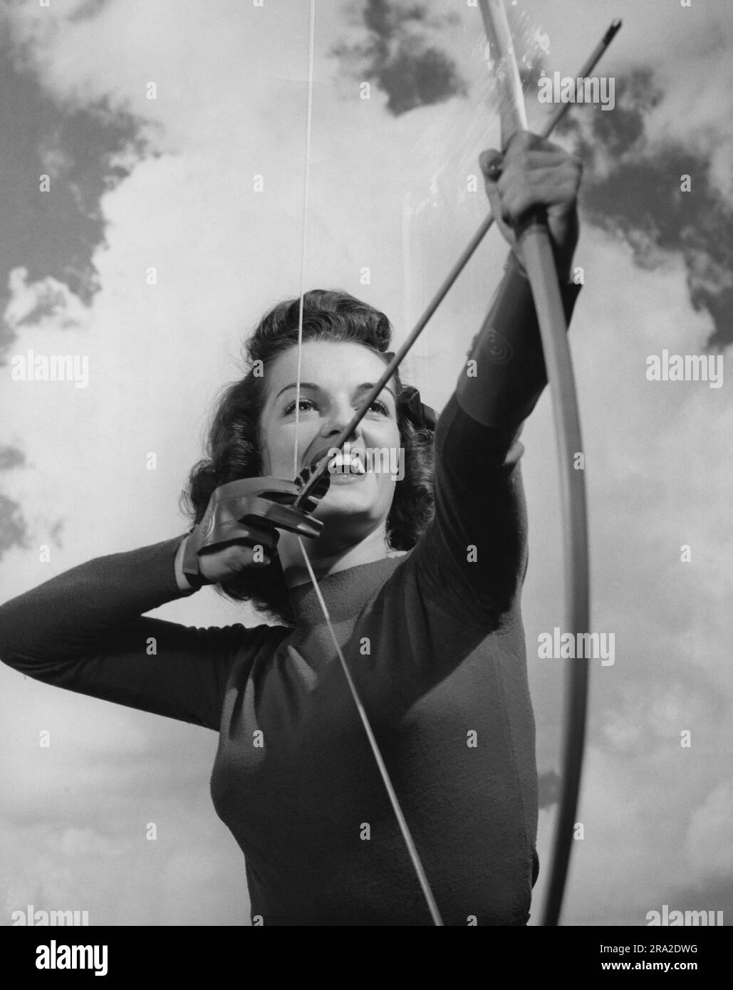 Young female archer pulling back the arrow about to shoot Stock Photo