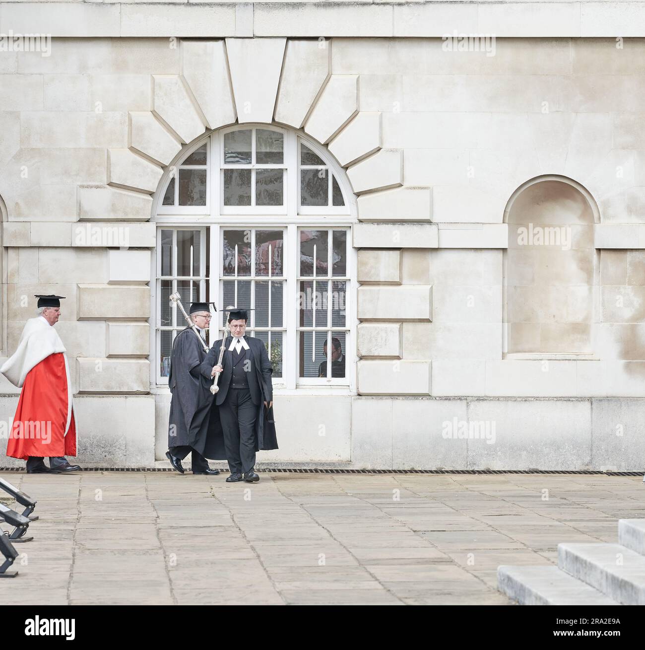 Esquire Bedells (mace bearers) in academic dress process with Sir