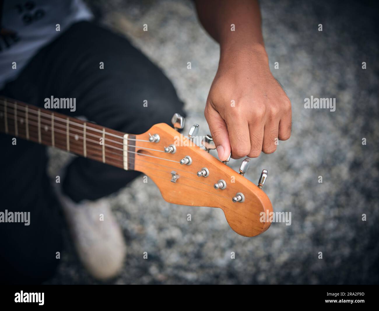 THE man indoors tuning guitar, front view and copy space. Stock Photo