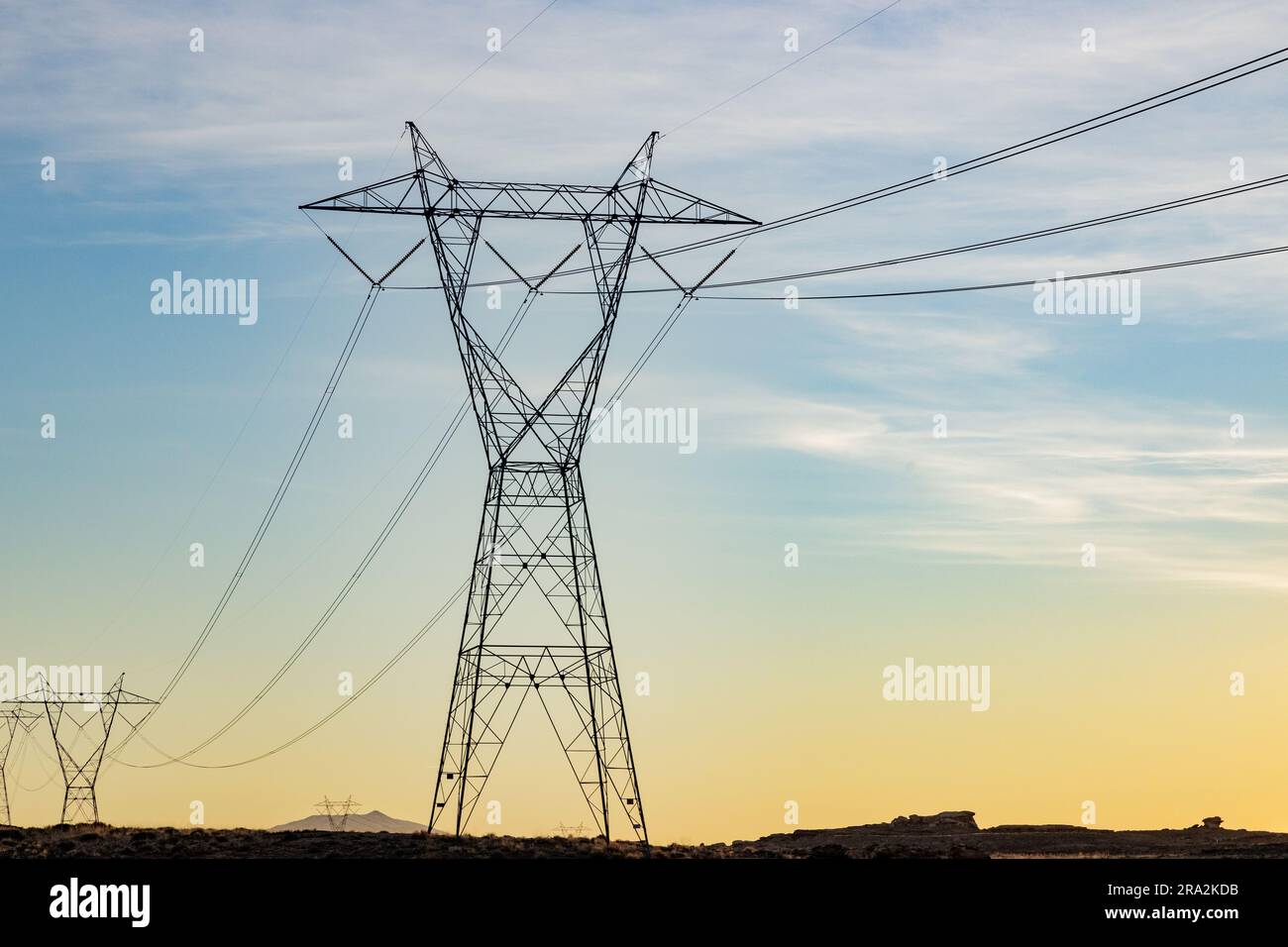 An open field dotted with power poles and crisscrossed with power lines ...