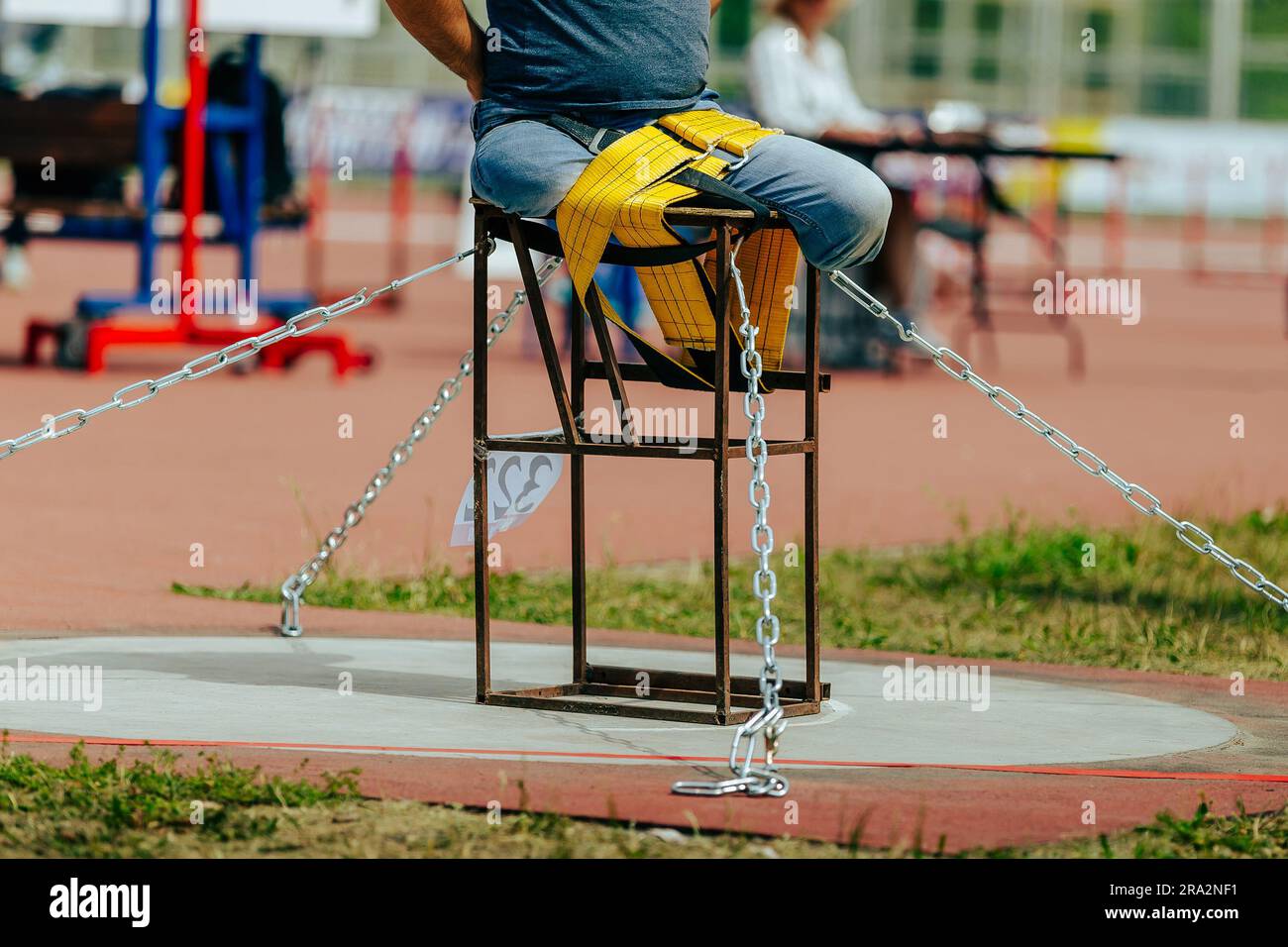 athlete without legs tied to table with belt shot put in para athletics, summer sports games Stock Photo
