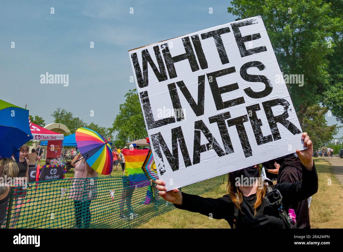 HUDSON, WI, USA - JUNE 17, 2023: Unidentified masked individual holding White Lives Matter banner at Hudson Pride celebration. Stock Photo