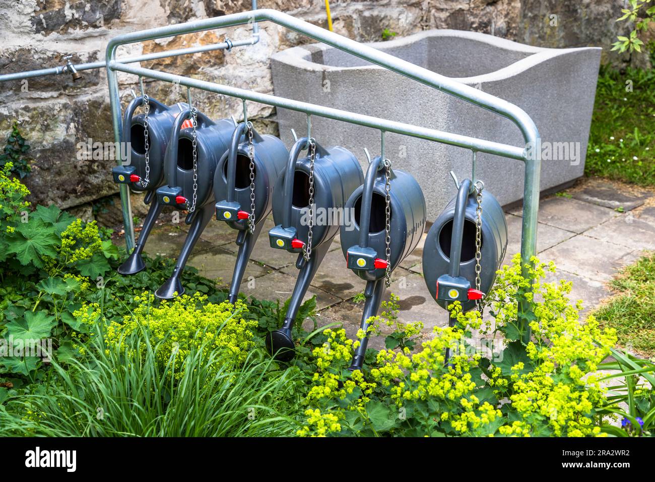 The cemetery regulations also apply to watering cans. Here watering cans for rent at the Trinitatisf cemetery in Dresden, Germany Stock Photo
