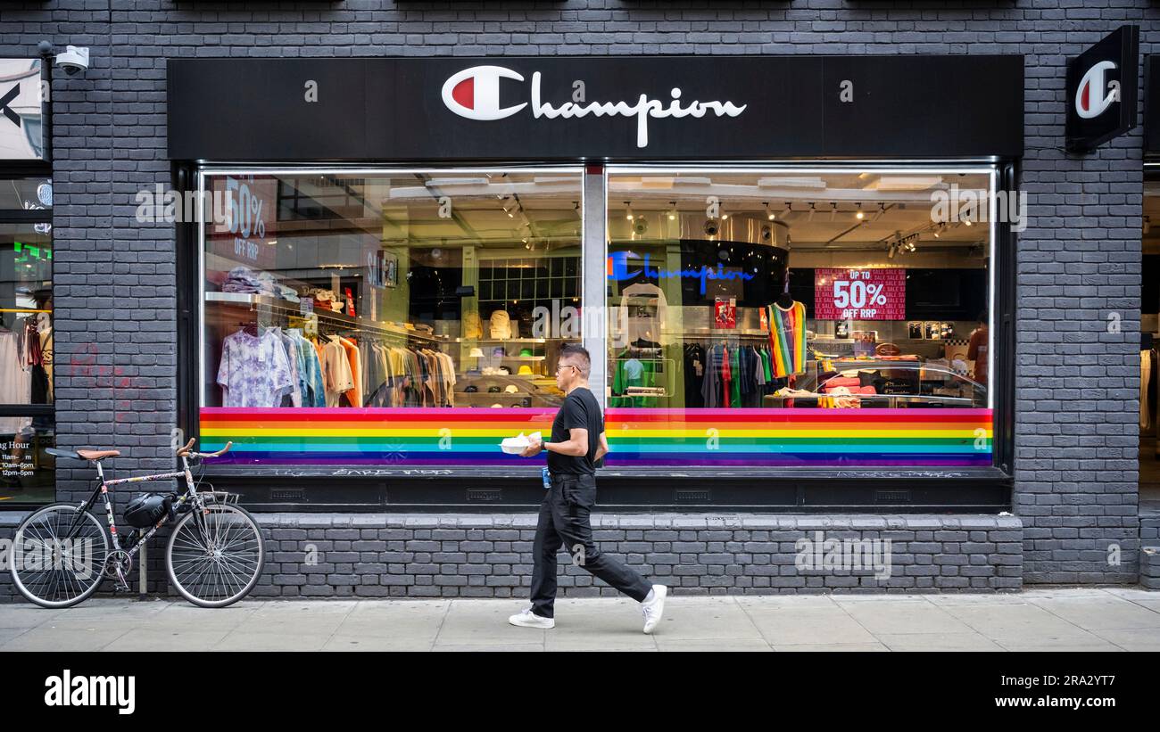 London, UK.  30 June 2023.  A man passes rainbow coloured decorations in the window of the Champion store in Brewer Street ahead of tomorrow’s Pride in London where thousands of visitors are expected to view and take part.  The event began in 1972 as a protest to bring attention to the LGBT community.  The original organisers, the Gay Liberation Front (GLF), have stated that Pride in London has become overly commercialised and dominated by corporations.  Credit: Stephen Chung / Alamy Live News Stock Photo