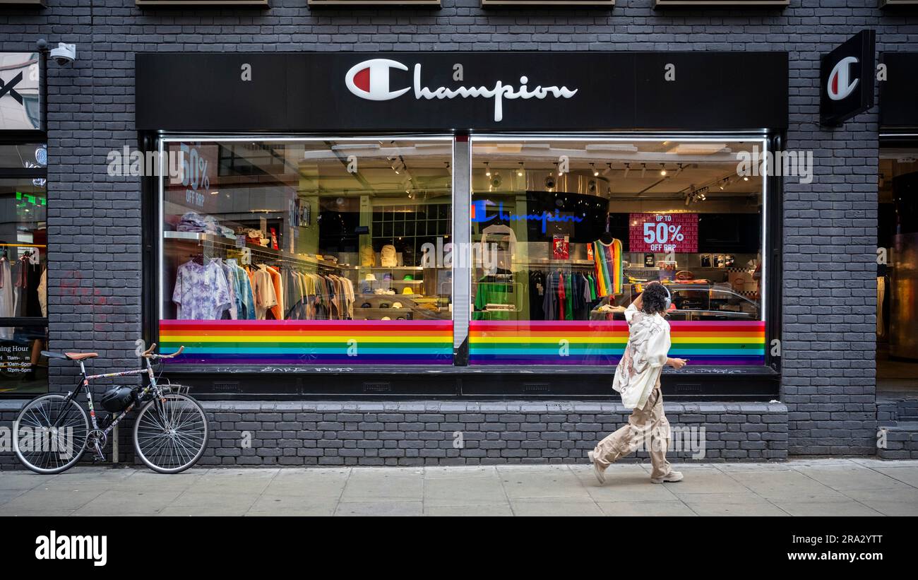 London, UK.  30 June 2023.  A person passes rainbow coloured decorations in the window of the Champion store in Brewer Street ahead of tomorrow’s Pride in London where thousands of visitors are expected to view and take part.  The event began in 1972 as a protest to bring attention to the LGBT community.  The original organisers, the Gay Liberation Front (GLF), have stated that Pride in London has become overly commercialised and dominated by corporations.  Credit: Stephen Chung / Alamy Live News Stock Photo