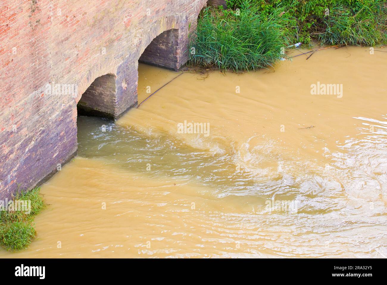 Dangerous, untreated, toxic polluted water flows from a city sewer to the river. Stock Photo