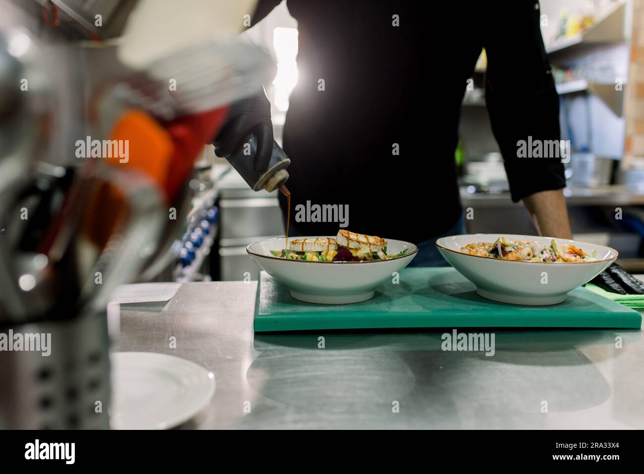 Crop anonymous male chef in black uniform serving delicious salad with ...