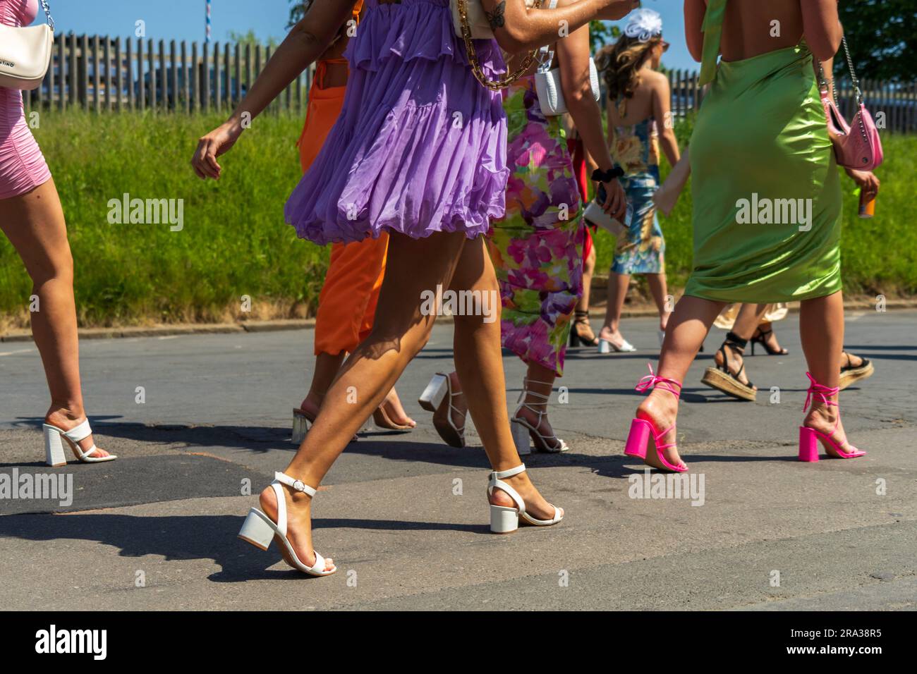 Stylish females, unrecognizable women, walk to racecourse entrance on race day in England. Horse racing is a popular sport and requires proper attire. Stock Photo